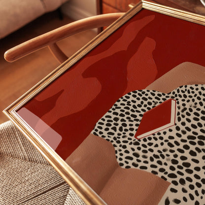a close-up view of a framed artwork with a red background and a black and white spotted pattern.