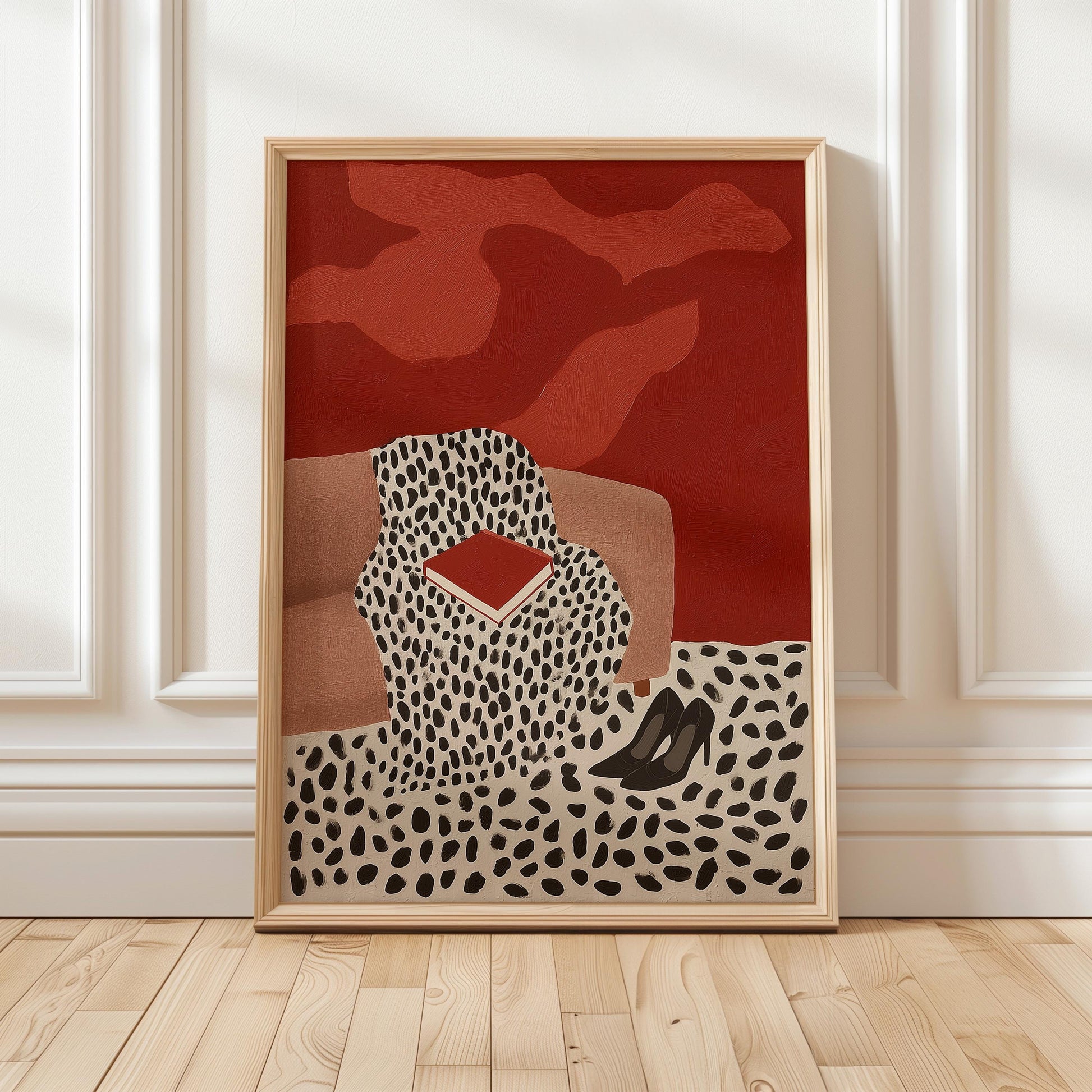 The image is a framed artwork depicting a woman sitting on a couch with a red and black patterned blanket, a pair of black high heels, and a red and black patterned pillow.