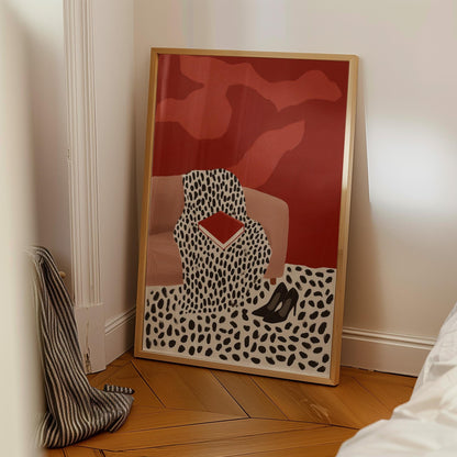 a large framed artwork with a striking red and black abstract design, including a pattern of black dots and a red shape, displayed on a wooden floor in a corner of a room.