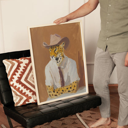 A person is holding up a framed painting of a leopard wearing a white shirt and a cowboy hat.
