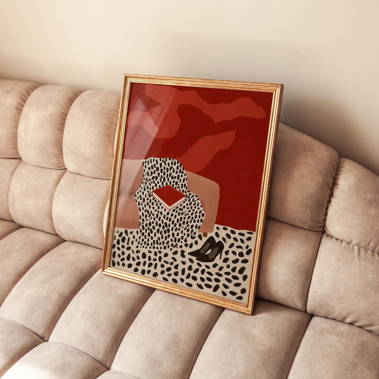 a framed artwork with a red background and a black and white pattern, depicting a woman sitting on a couch.