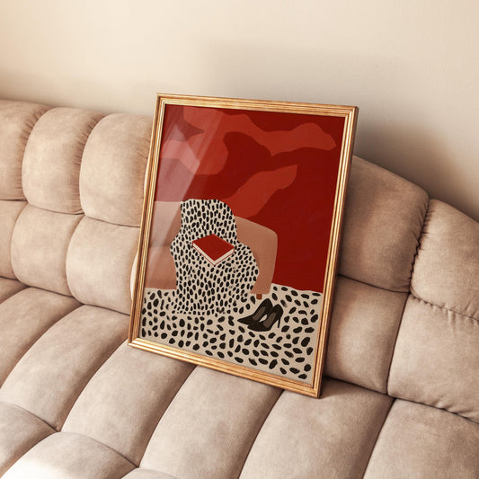 a framed artwork with a red background and a black and white pattern, depicting a woman sitting on a couch.