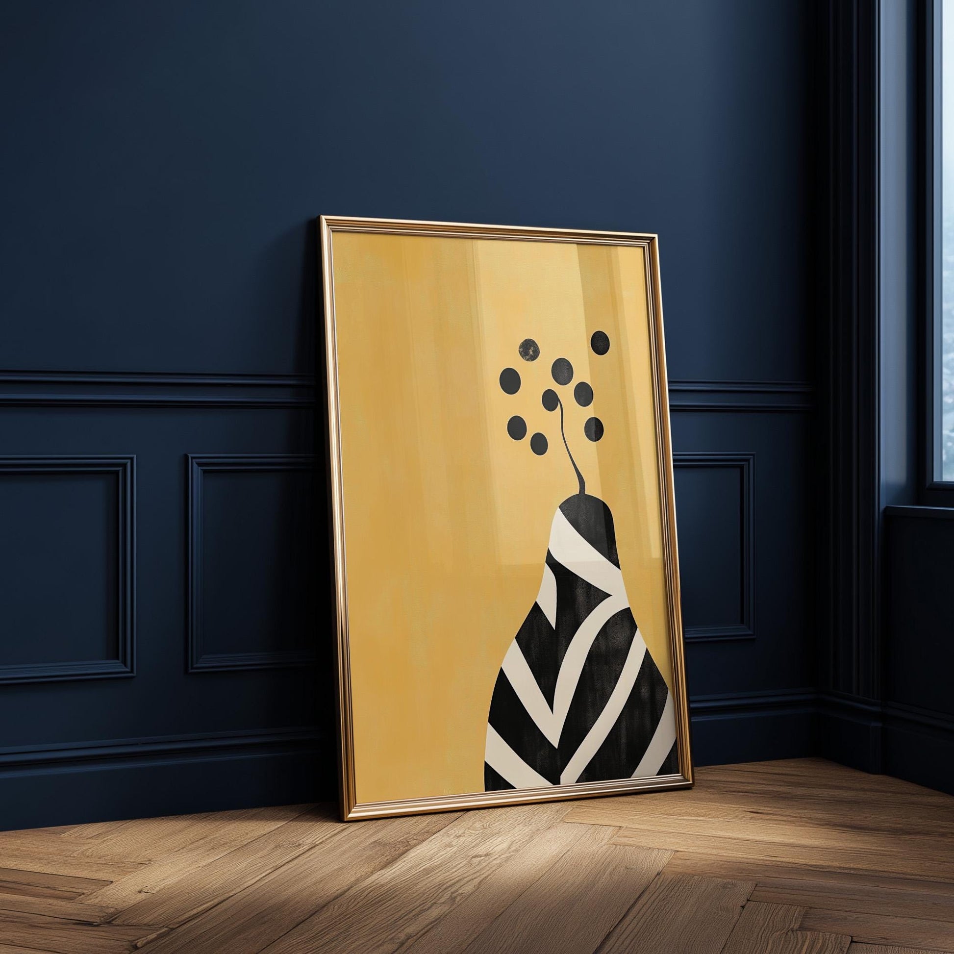 a framed artwork with a black and white abstract design on a yellow background, placed on a wooden floor against a dark blue wall.