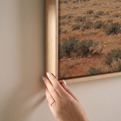 Lone cowboy riding across a sagebrush plain below red desert mesas and buttes, horizontal canvas print