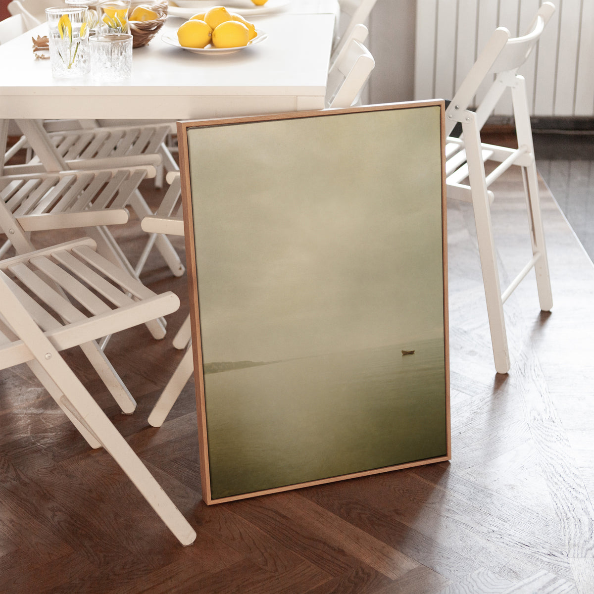 Boat canvas wall art showing a single small boat on flat pale water with a distant headland in mist