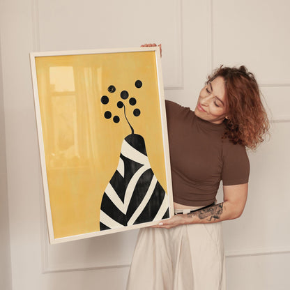 A woman holding a framed artwork with a yellow background and a black and white abstract design.