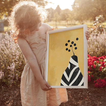 A young girl in a beige dress holds a framed picture of a stylized flower with black and white stripes in a garden setting.