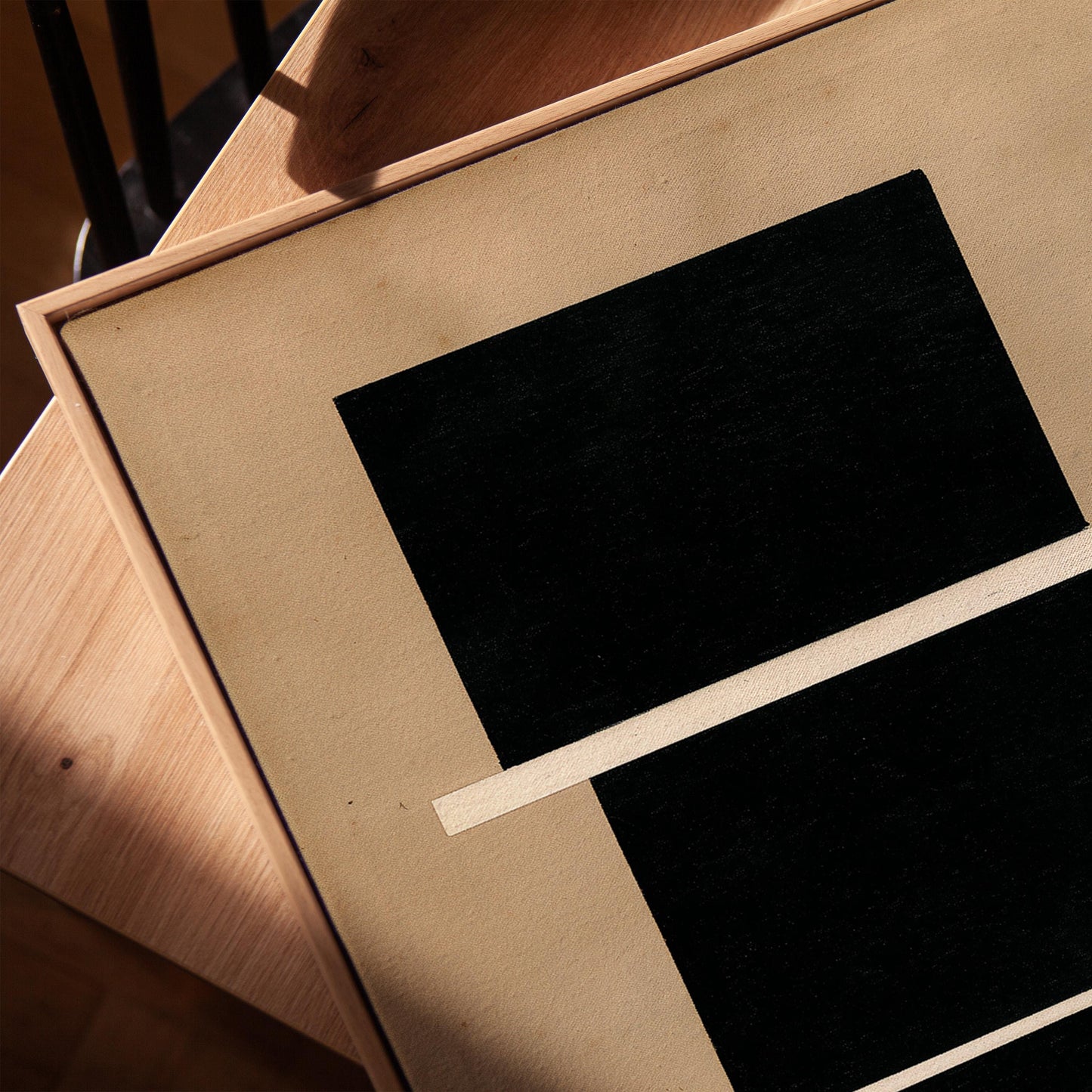 a close-up view of a black and white abstract artwork, with a wooden surface and a shadow visible in the background.
