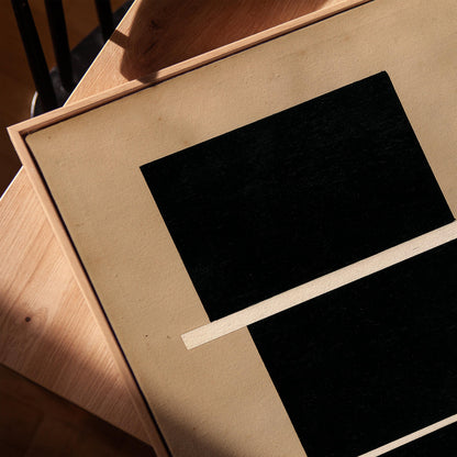 a close-up view of a black and white abstract artwork, with a wooden surface and a shadow visible in the background.