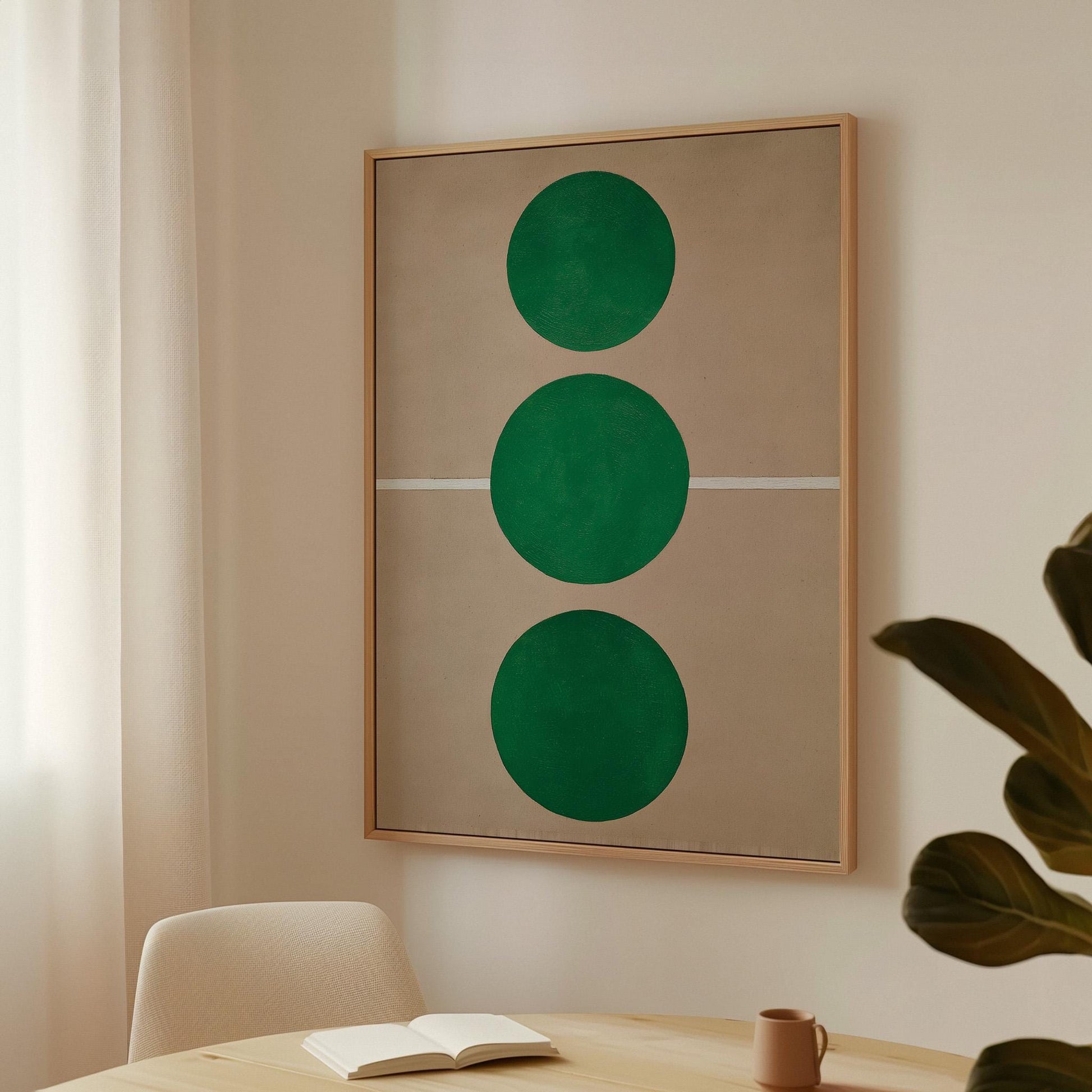 a minimalist interior design with a large framed artwork hanging on the wall, depicting three green circles arranged vertically. In the foreground, there is a table with a book and a mug, and a plant is visible in the background.