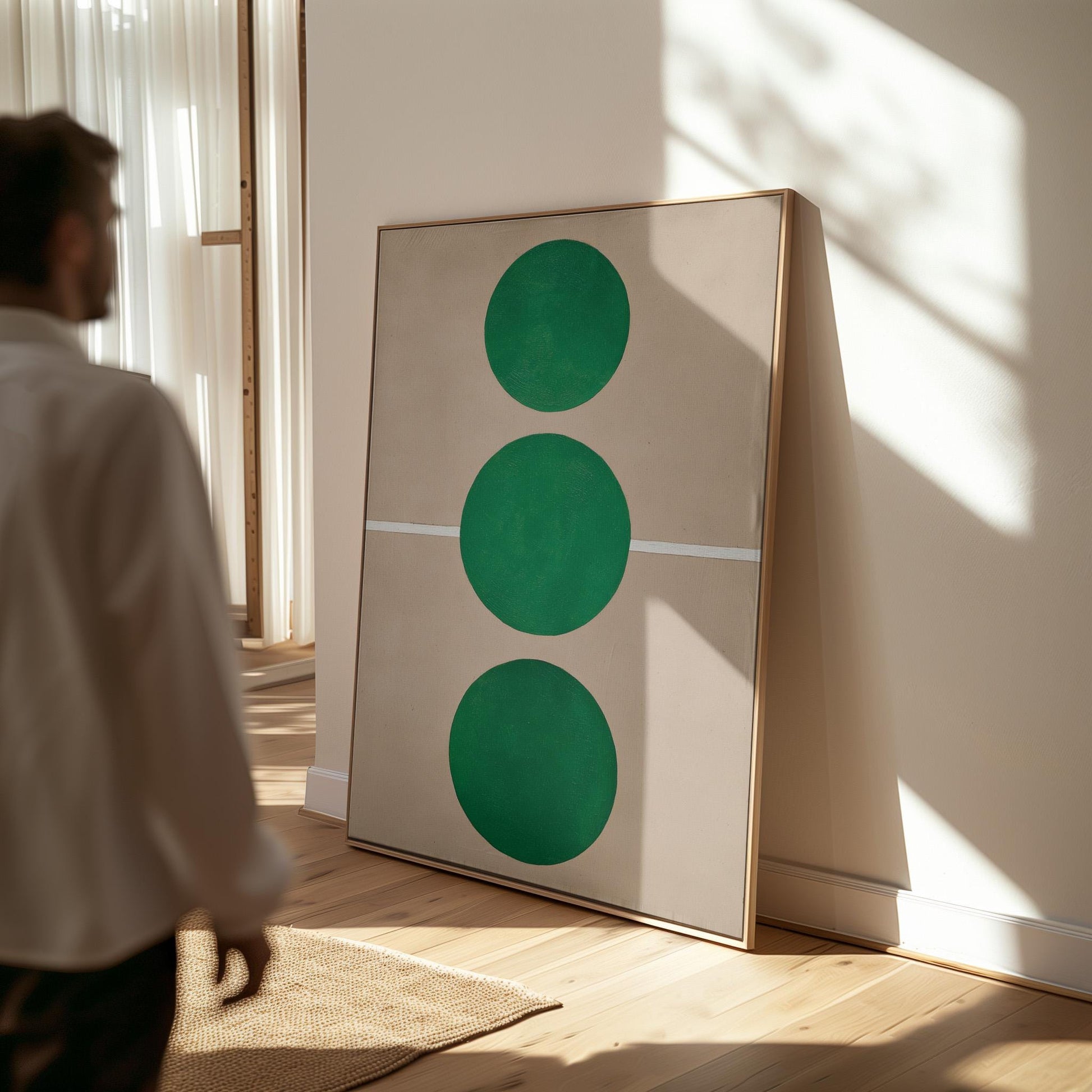 a person standing in a room with a large framed artwork on the wall, which consists of three green circles.