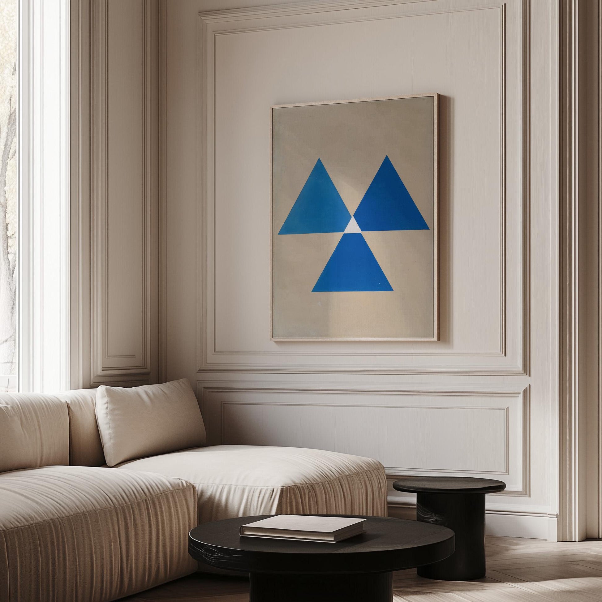 a modern living room with a large window, a white sofa, and a framed abstract artwork featuring blue triangles on the wall.