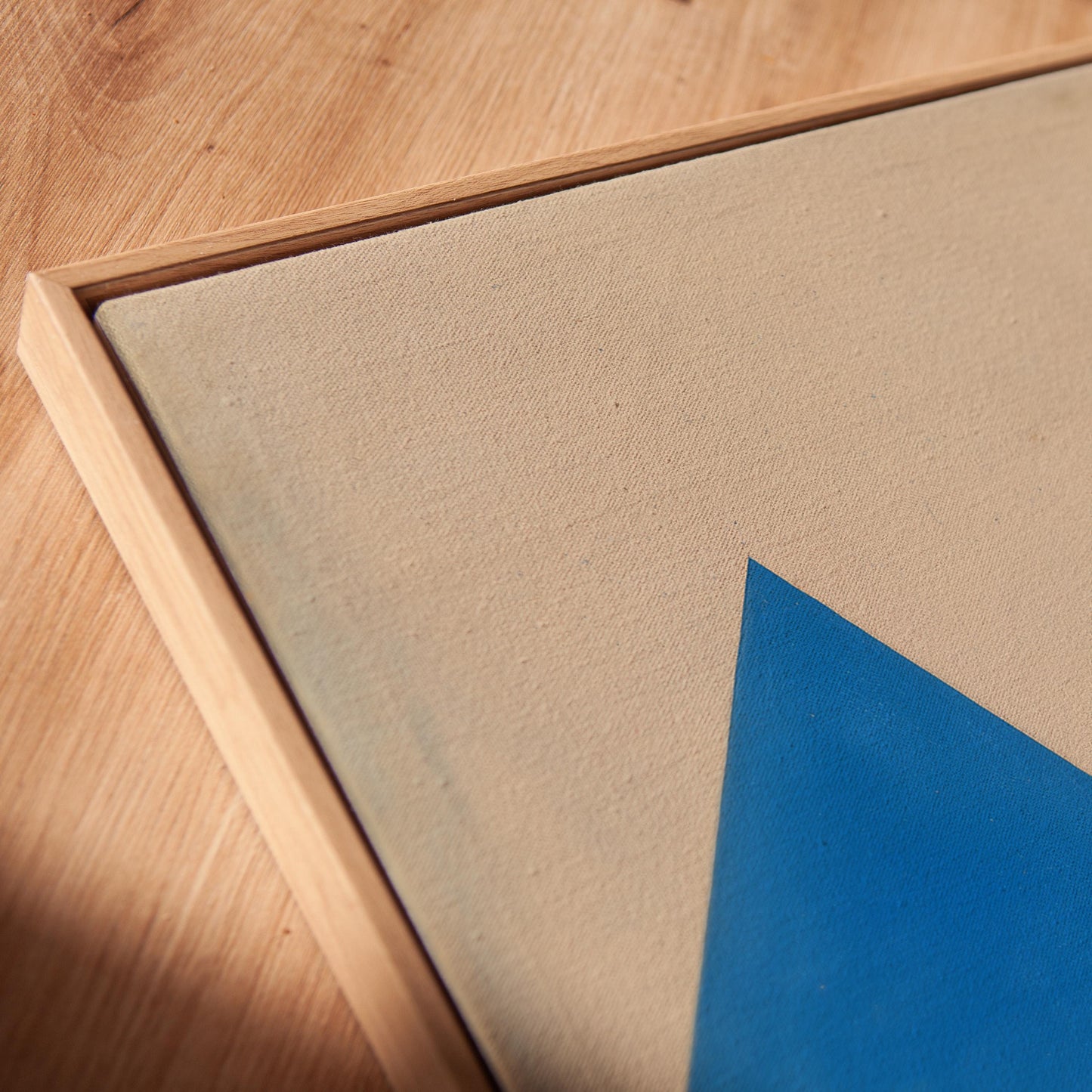 a close-up view of a wooden surface with a framed artwork featuring a blue triangle on it.
