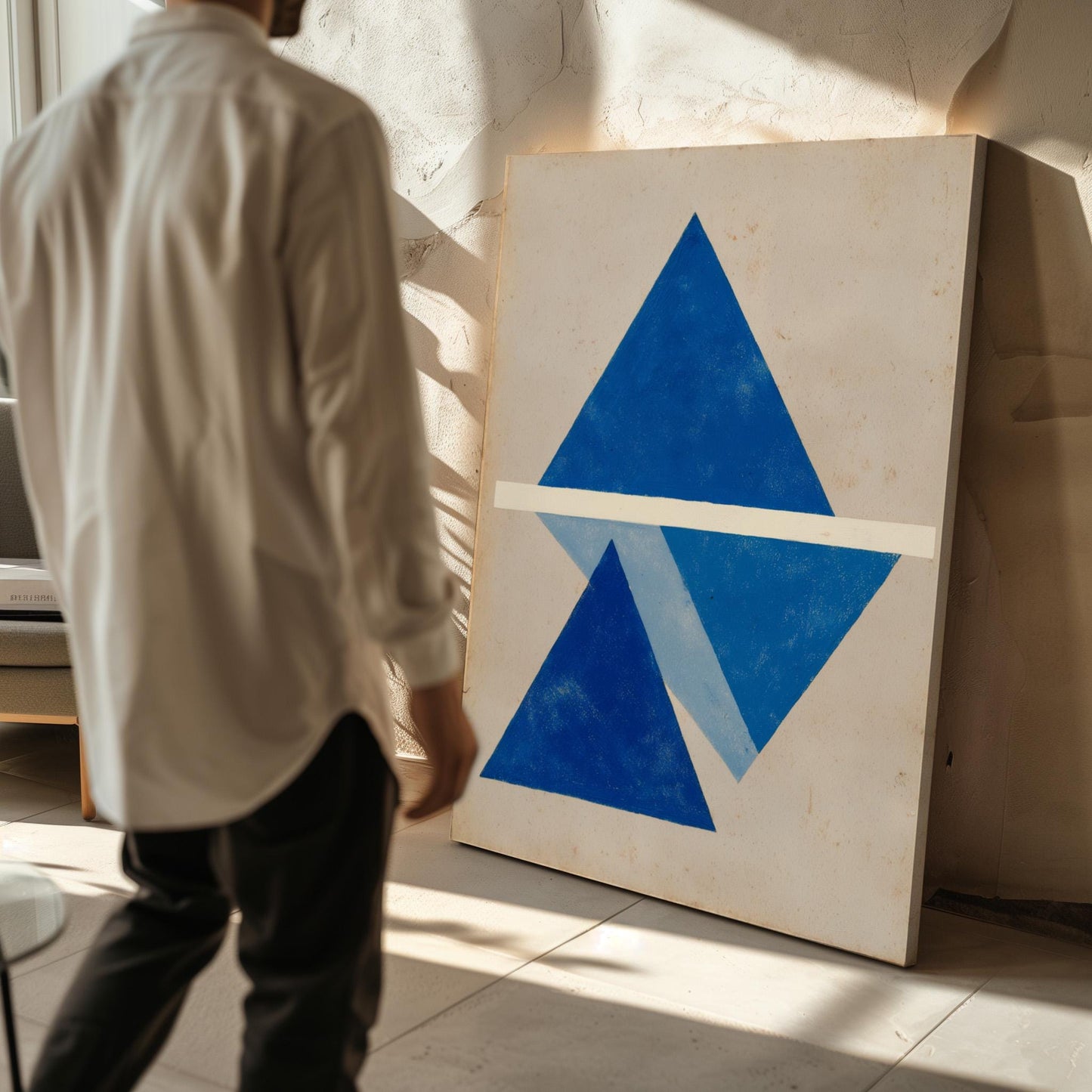 A person is standing in front of a large painting that features a blue triangle and a white line, creating an abstract composition.