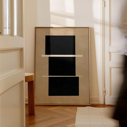 a large, abstract painting with a black background and three white rectangles arranged in a horizontal line. The painting is displayed on a white wall, and there is a wooden stool in the foreground.