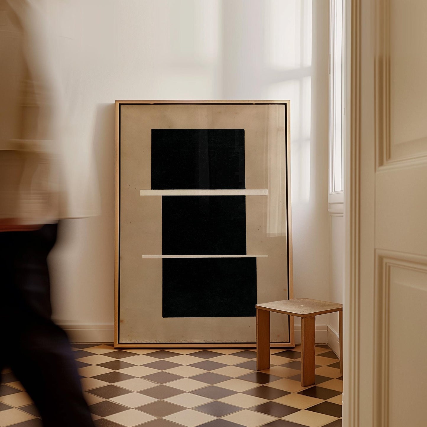 a large black square framed in gold, placed on a checkered floor in a room with a wooden stool and a window.