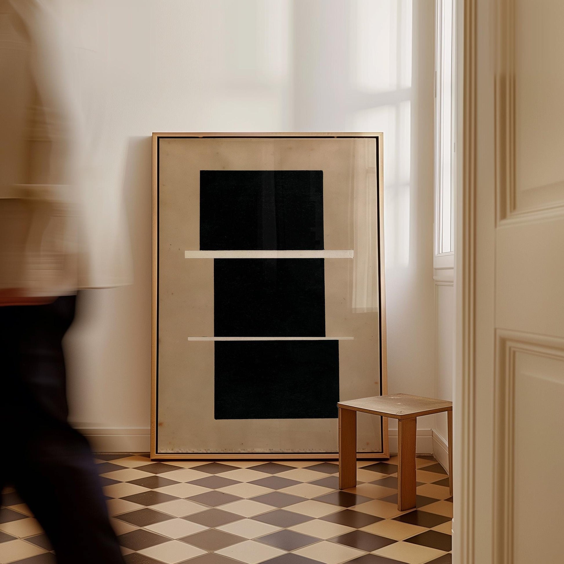 a large black square framed in gold, placed on a checkered floor in a room with a wooden stool and a window.