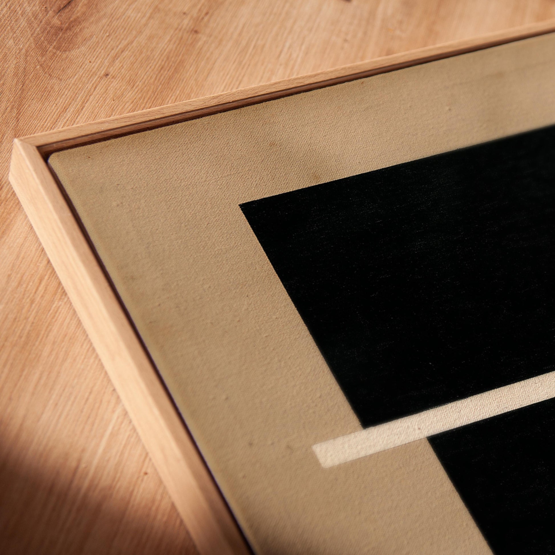 a close-up view of a wooden surface with a framed artwork featuring a black square and a white line.