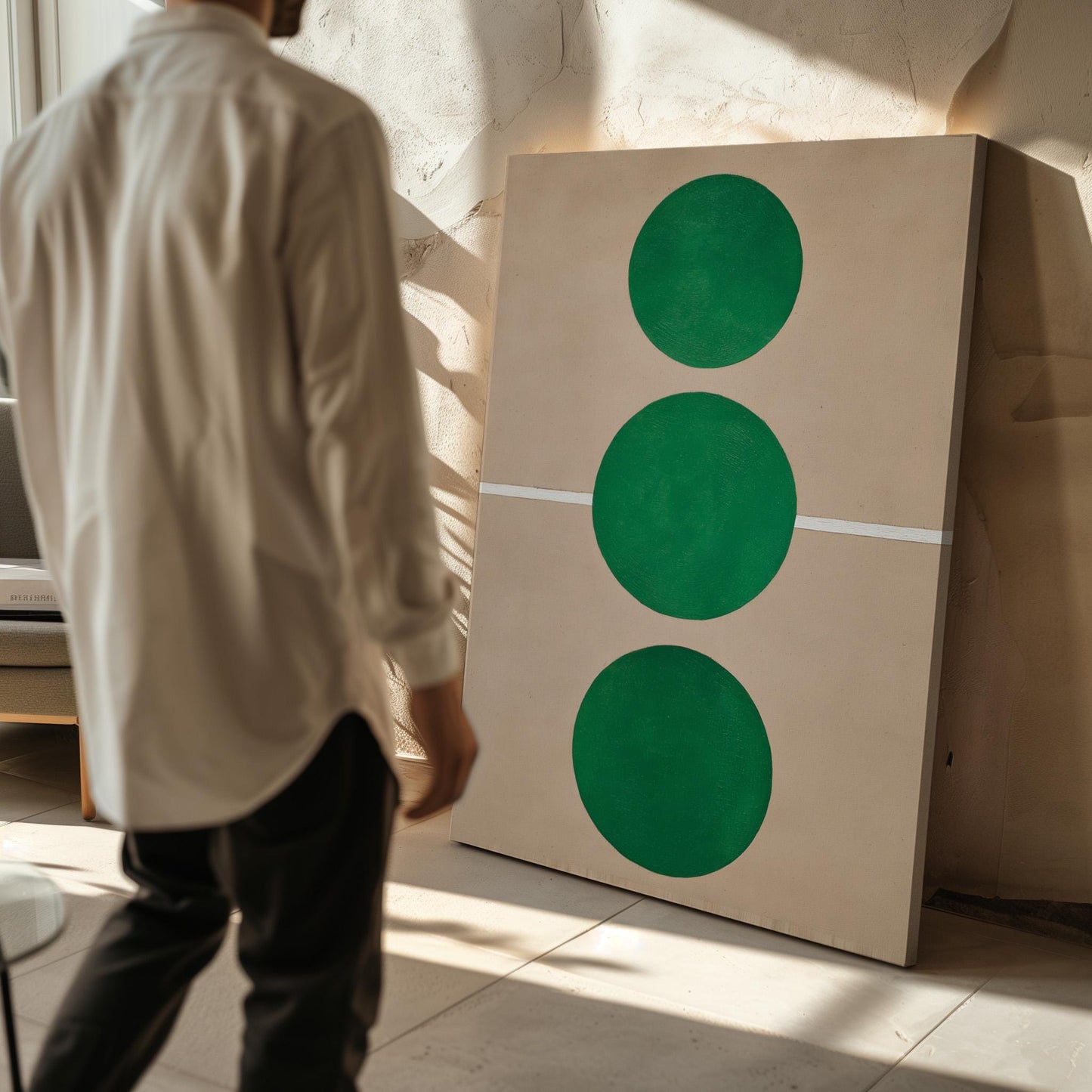A person is standing in front of a large painting that features three green circles on a beige background.