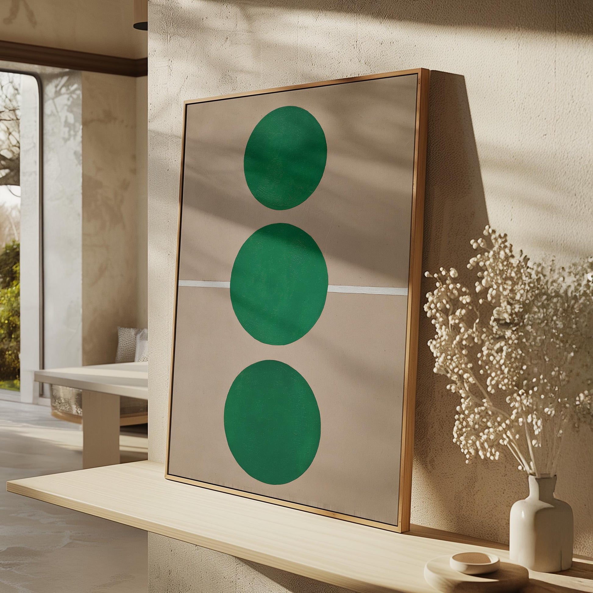 a minimalist interior design with a large framed artwork featuring three green circles on a beige wall, accompanied by a vase of white flowers and a wooden shelf.