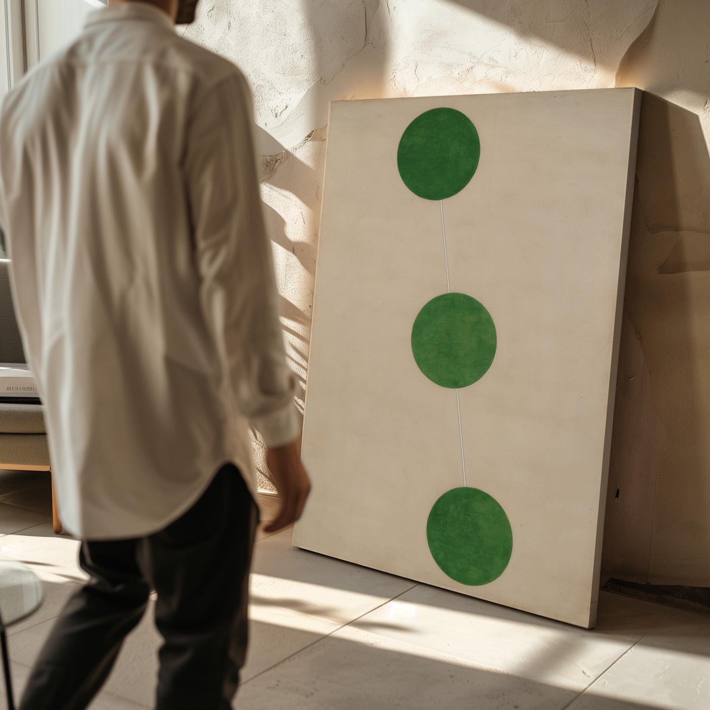 A person is standing in front of a large painting with three green circles on a white background.