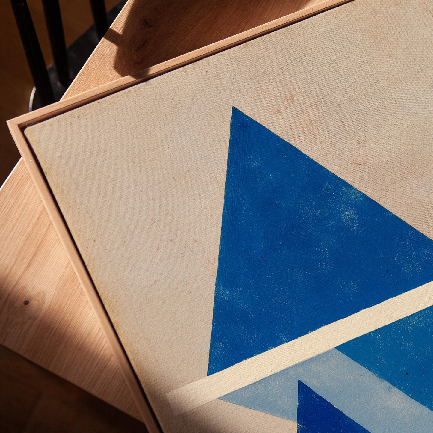 a close-up view of a painting with a blue triangle on a white background.