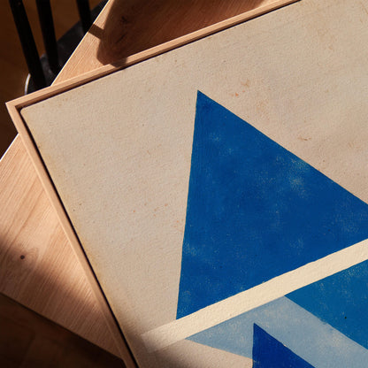 a close-up view of a painting with a blue triangle on a white background.