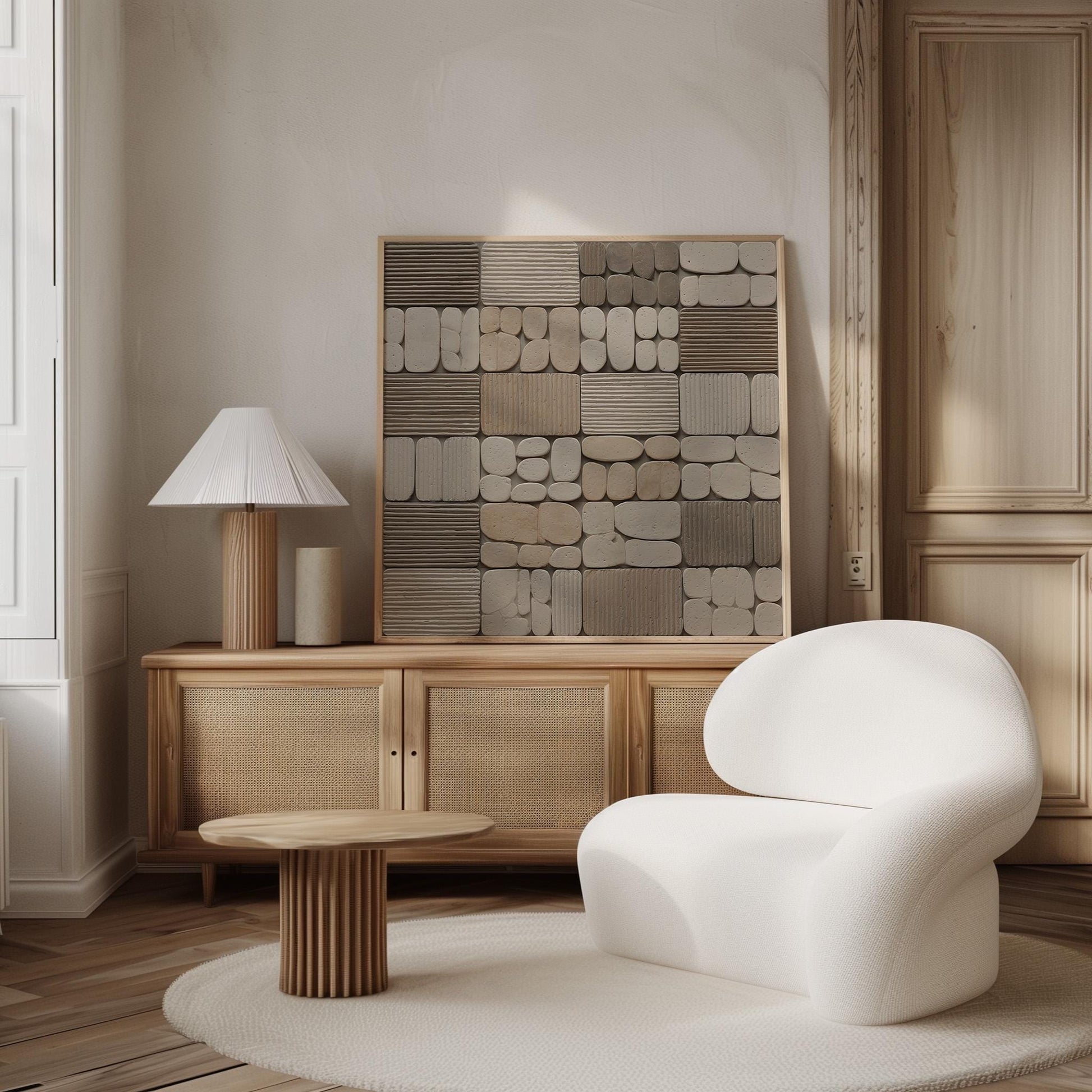 a minimalist living room with a white chair, a wooden sideboard, and a wooden table. The room has a neutral color palette with a large abstract artwork on the wall.