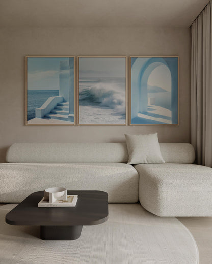 a modern living room with a white sofa, a black coffee table, and three framed pictures on the wall above the sofa.