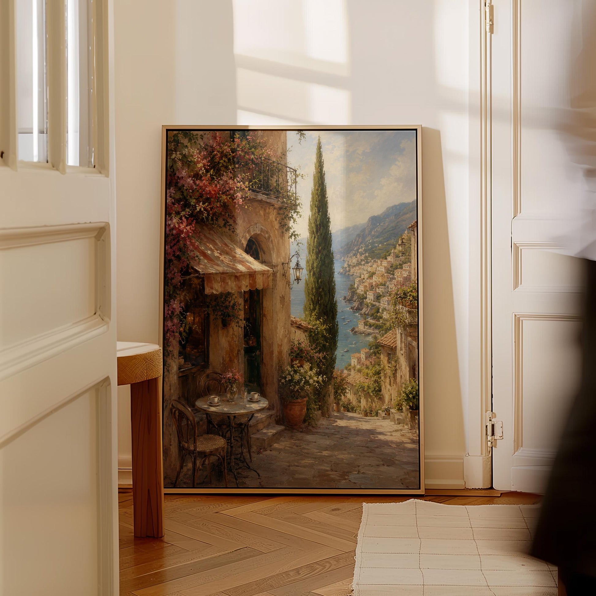 Italian village cafe painting with striped awning and coastal view, canvas print styled against a soft white wall