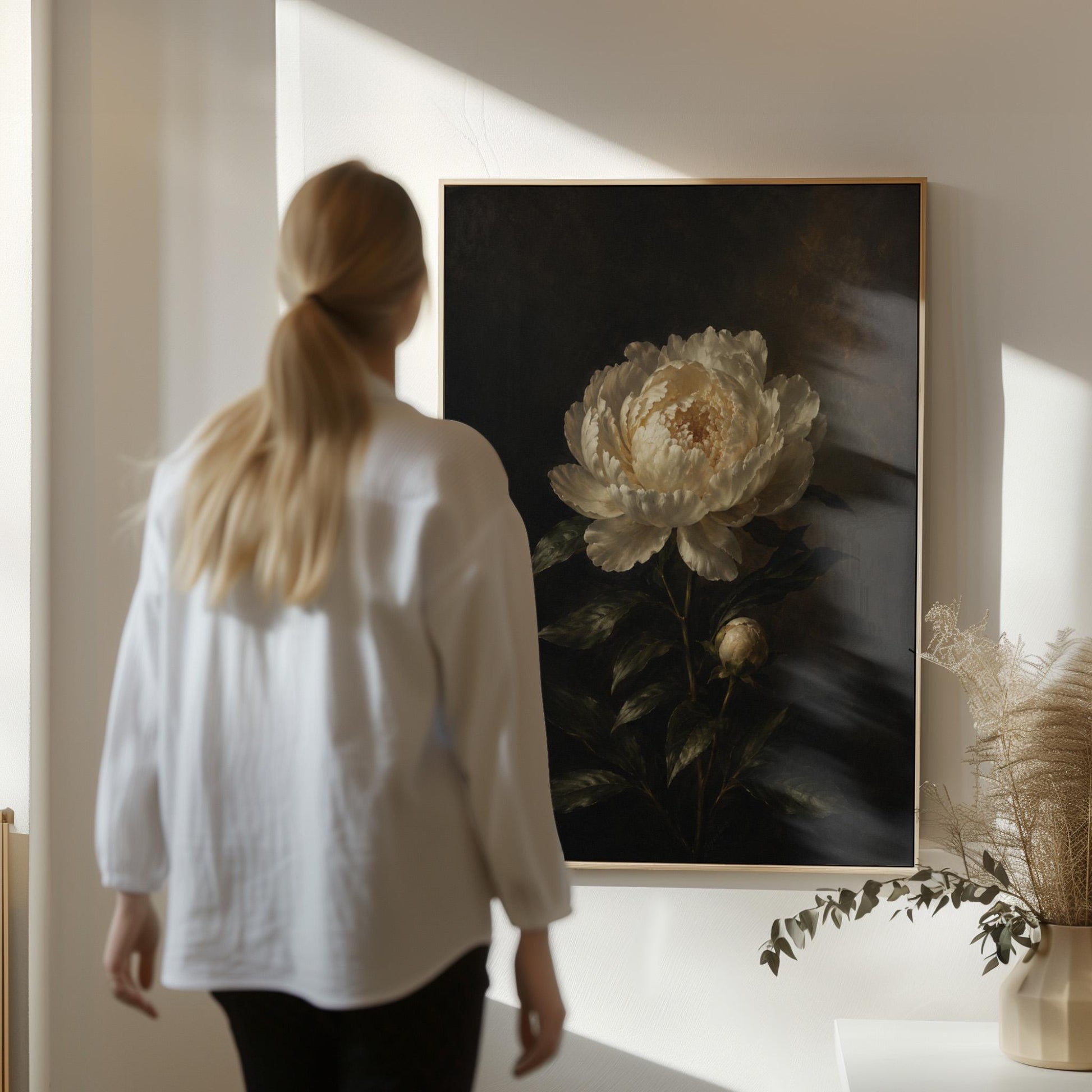 White peony in full bloom against a dark background, canvas print shown to scale in a furnished room