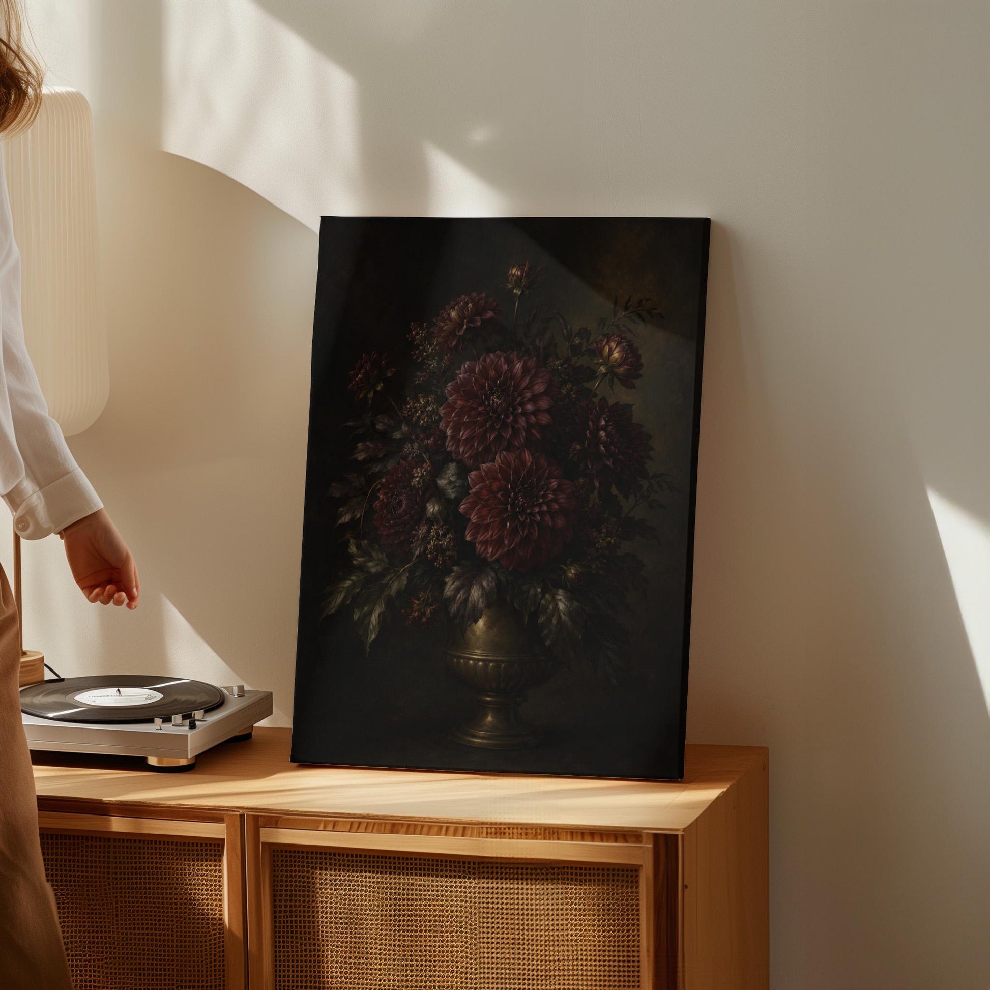 Burgundy dahlias in a brass urn against darkness, canvas print shown in a sunlit, contemporary room