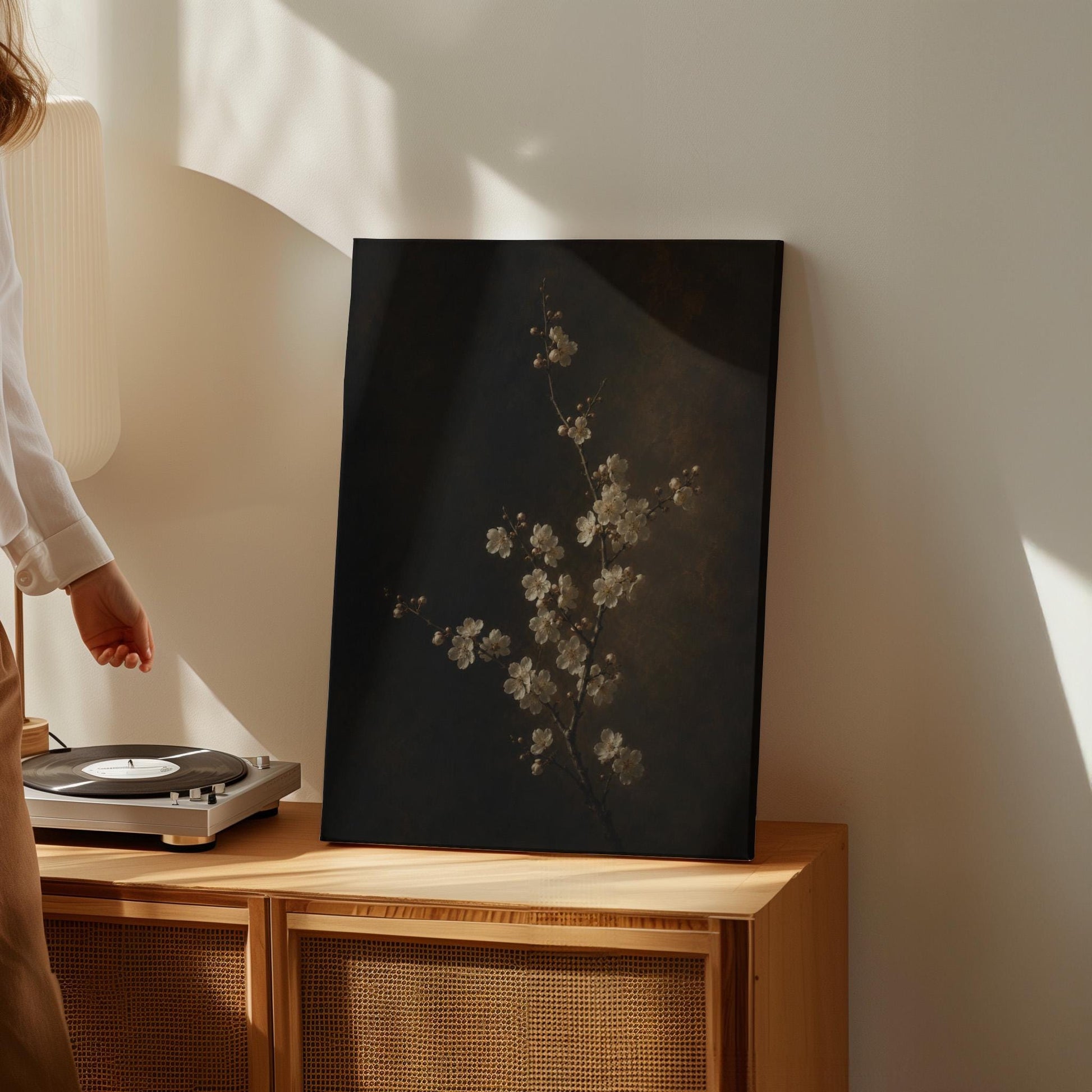 White blossom branch on a dark bronze ground, canvas print shown to scale in a furnished room