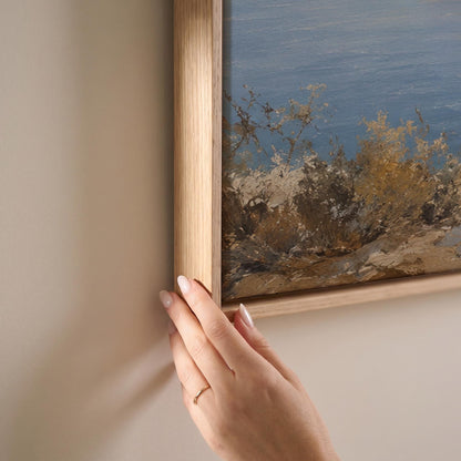 Three horses on a coastal bluff above a blue sea, canvas print shown at full size in a light-filled bedroom