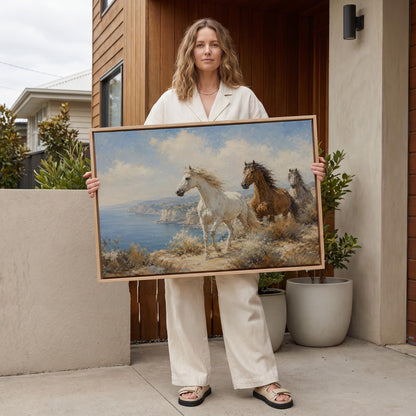 Three horses on a coastal bluff above a blue sea, canvas print shown in a sunlit, contemporary room