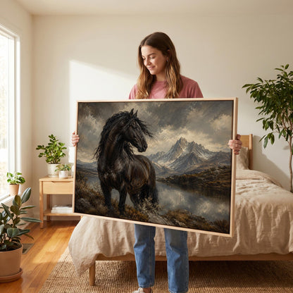 Black Friesian horse by a mountain lake under storm light, canvas print shown to scale in a furnished room