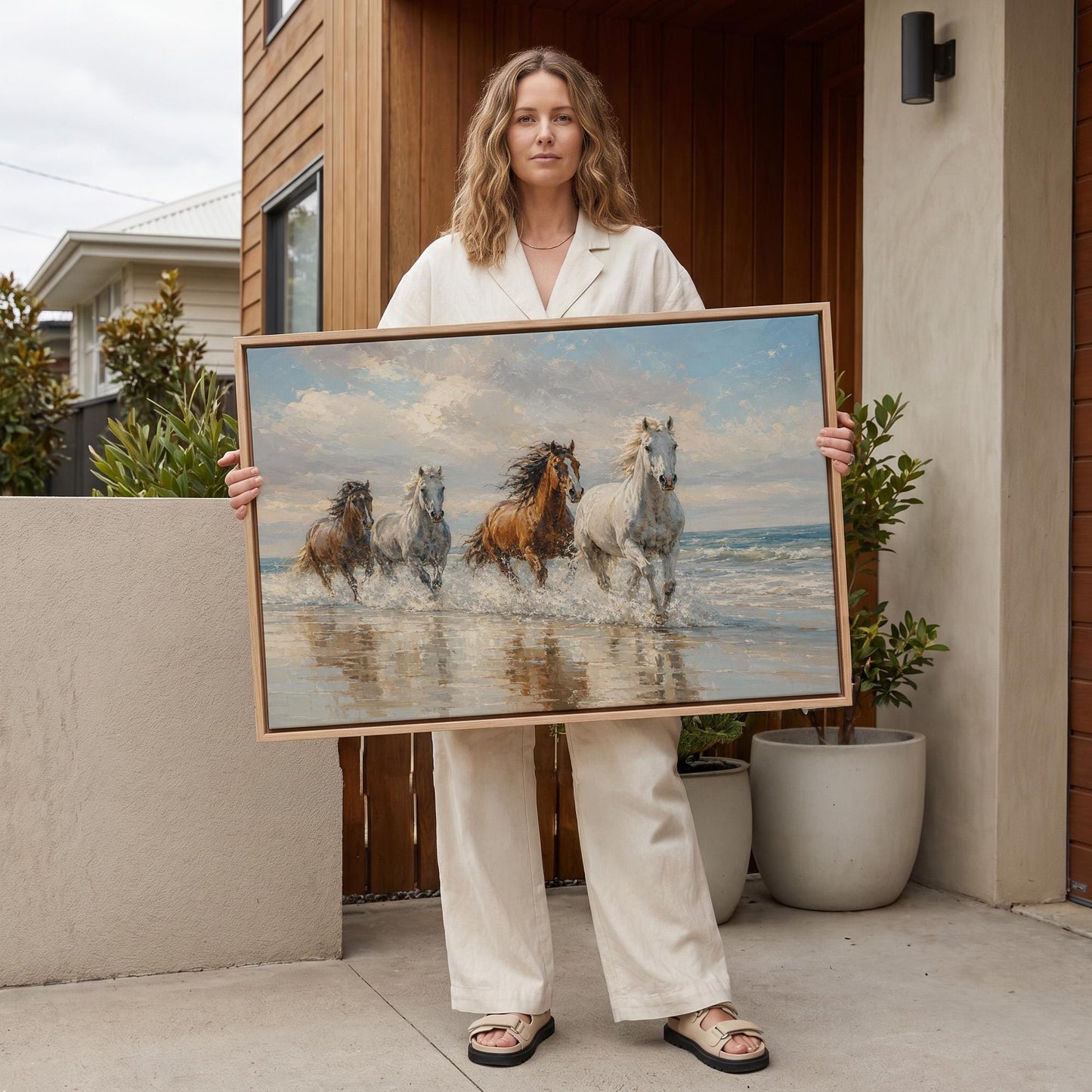 Four horses running through shallow surf on a beach, canvas print styled against a soft white wall