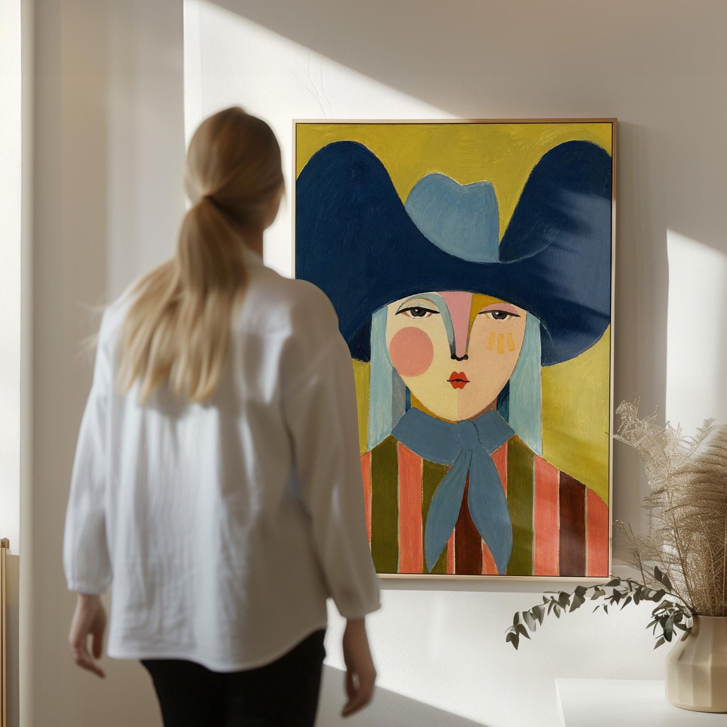 Folk cowgirl in an oversized navy hat and blue neckerchief on mustard, canvas wall art on a quiet wall in a considered interior