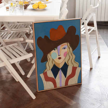Blonde cowgirl in a rust cowboy hat with a cubist face on deep blue, canvas print seen in a warm interior with natural light