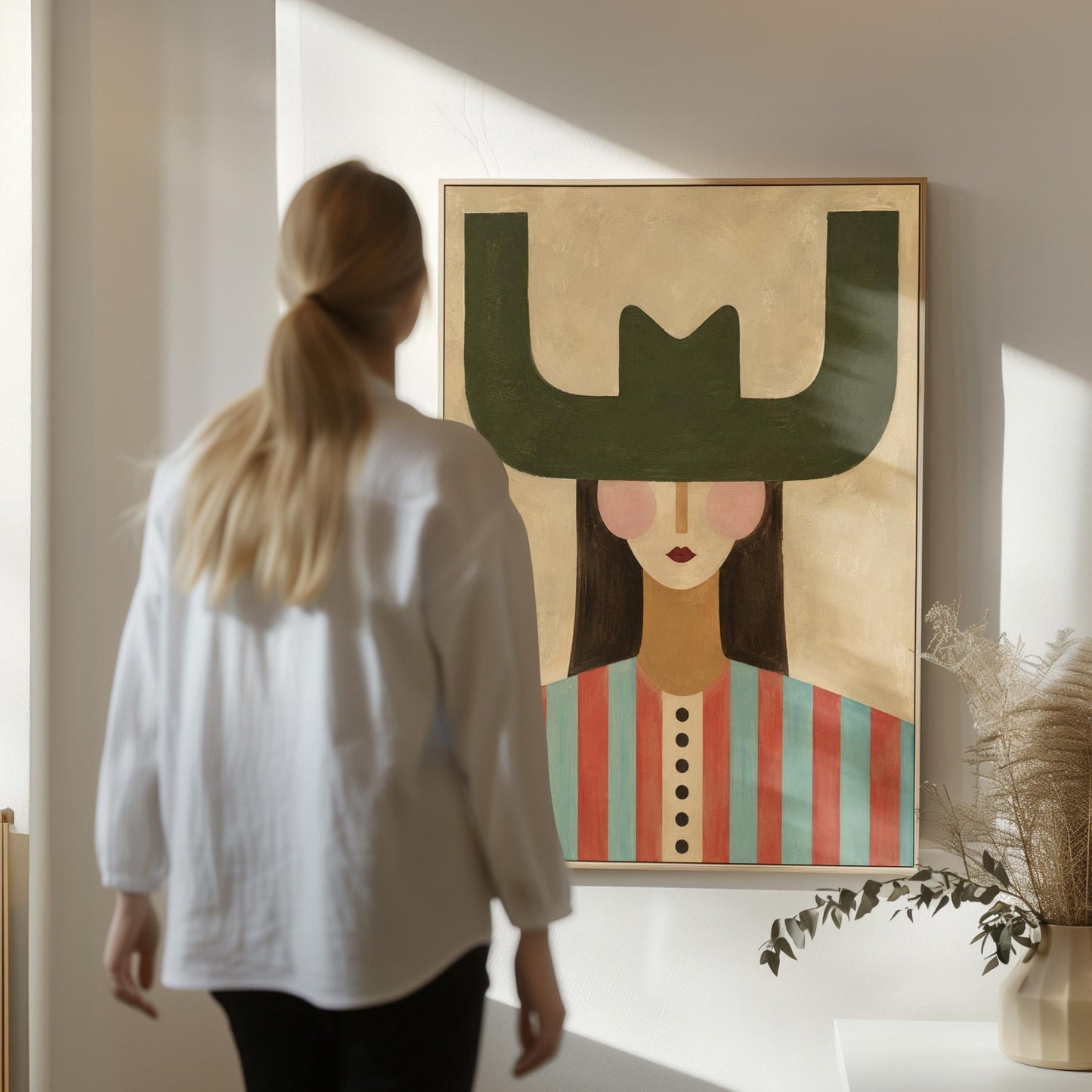 Minimal cowgirl with a bold green hat and red-teal striped shirt on cream, canvas print shown to scale in a furnished room
