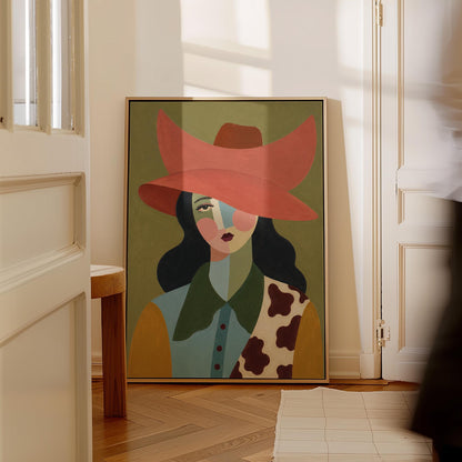 Cowgirl in a wide coral hat with a cubist face and cow-print collar on olive, canvas wall art styled against a soft white wall