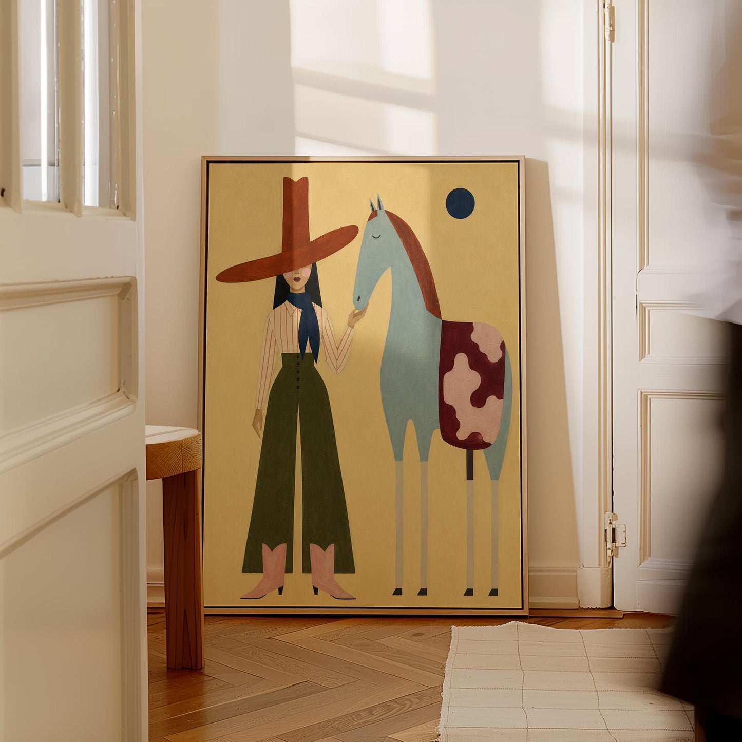Cowgirl in a red hat standing beside a pale blue spotted horse on warm yellow, canvas wall art on a quiet wall in a considered interior