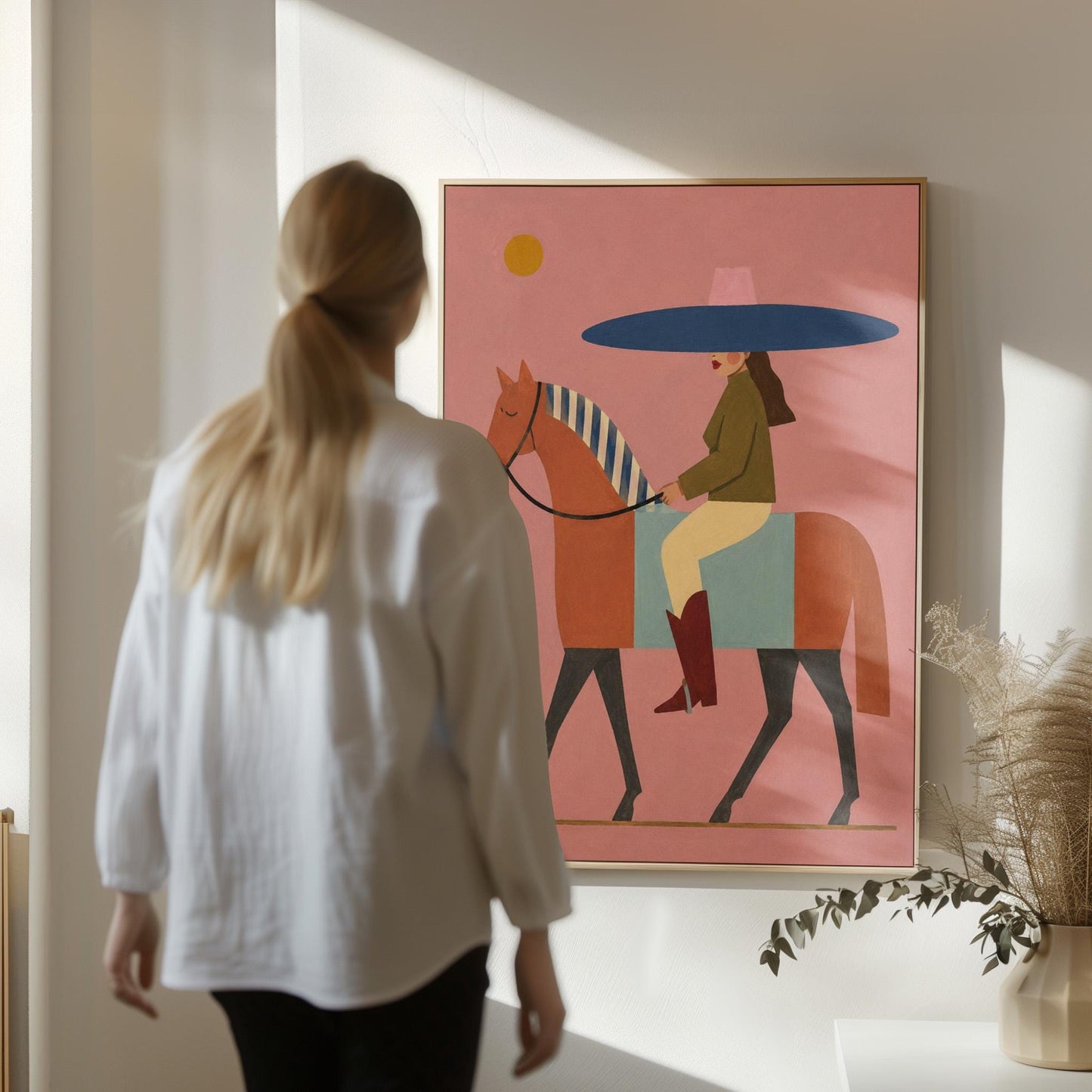 Woman in a wide navy hat riding a chestnut horse in profile on coral pink, canvas print styled against a soft white wall