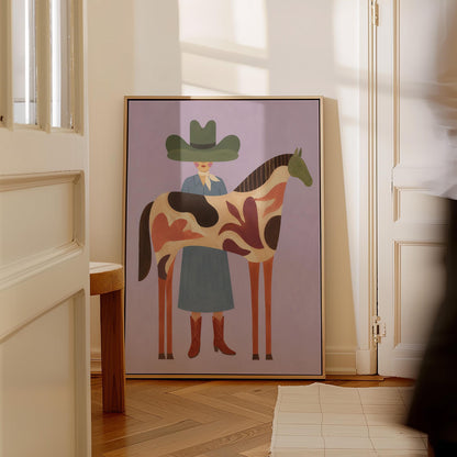 Cowgirl in a green hat beside a tall patterned horse on soft lilac, canvas print shown to scale in a furnished room
