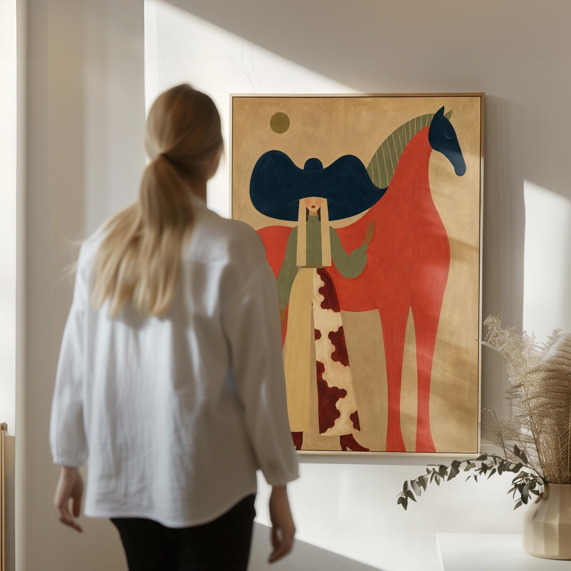 Woman in a big navy hat standing before a bright red horse on warm ochre, canvas print shown in a sunlit, contemporary room