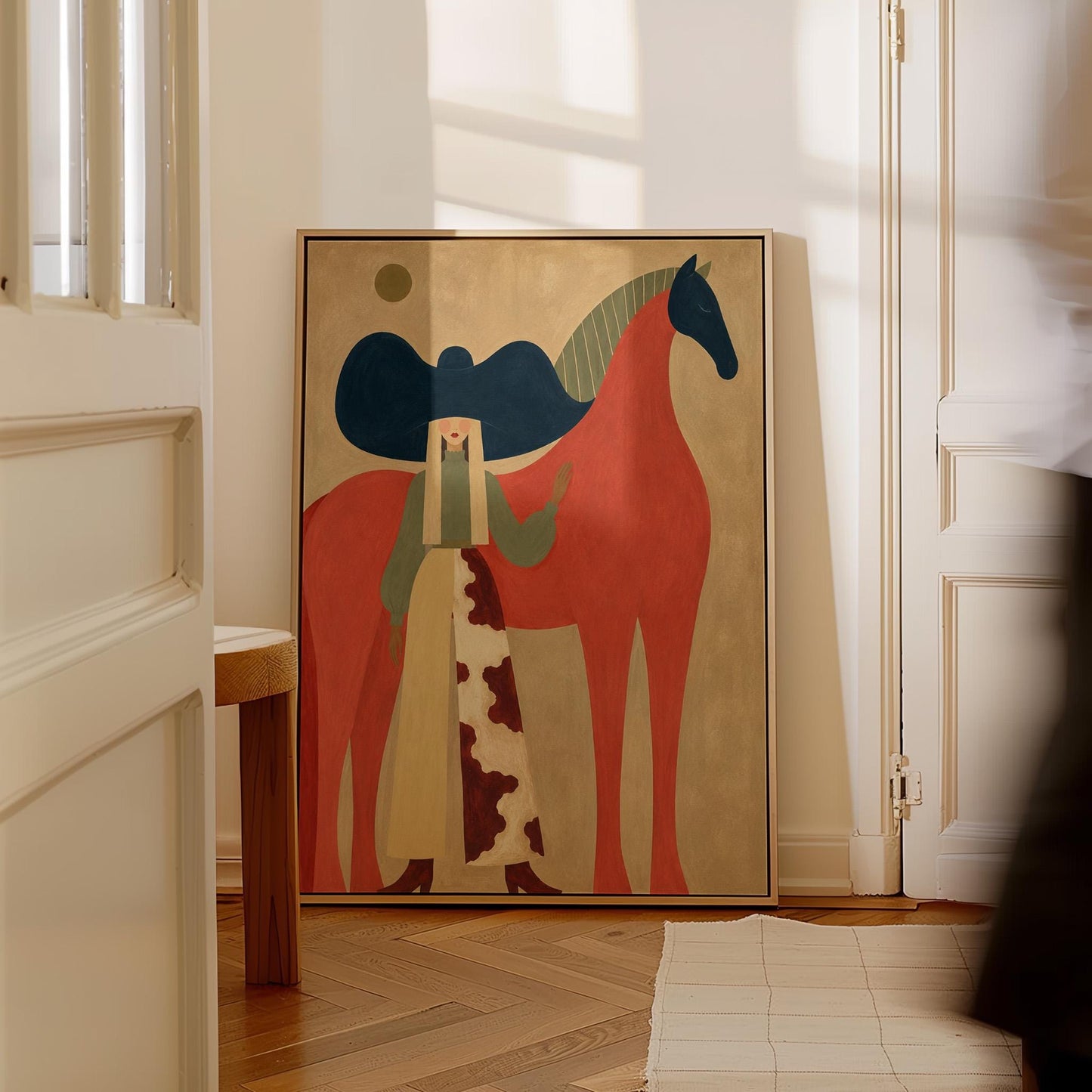 Woman in a big navy hat standing before a bright red horse on warm ochre, canvas wall art on a quiet wall in a considered interior