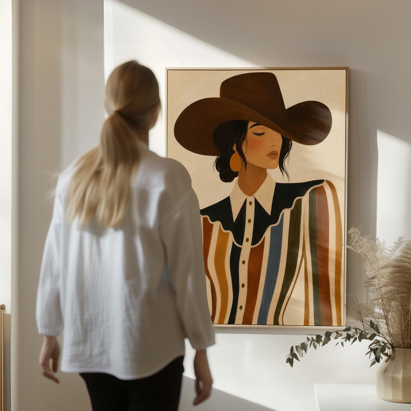 Cowgirl in a brown hat and rippling striped blouse with a black collar on cream, canvas wall art styled against a soft white wall