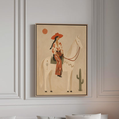 Cowgirl in a red hat sitting on a white horse beside a cactus in warm sand, canvas print in a bright room with natural daylight