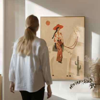 Cowgirl in a red hat sitting on a white horse beside a cactus in warm sand, canvas print presented in a light, minimal room
