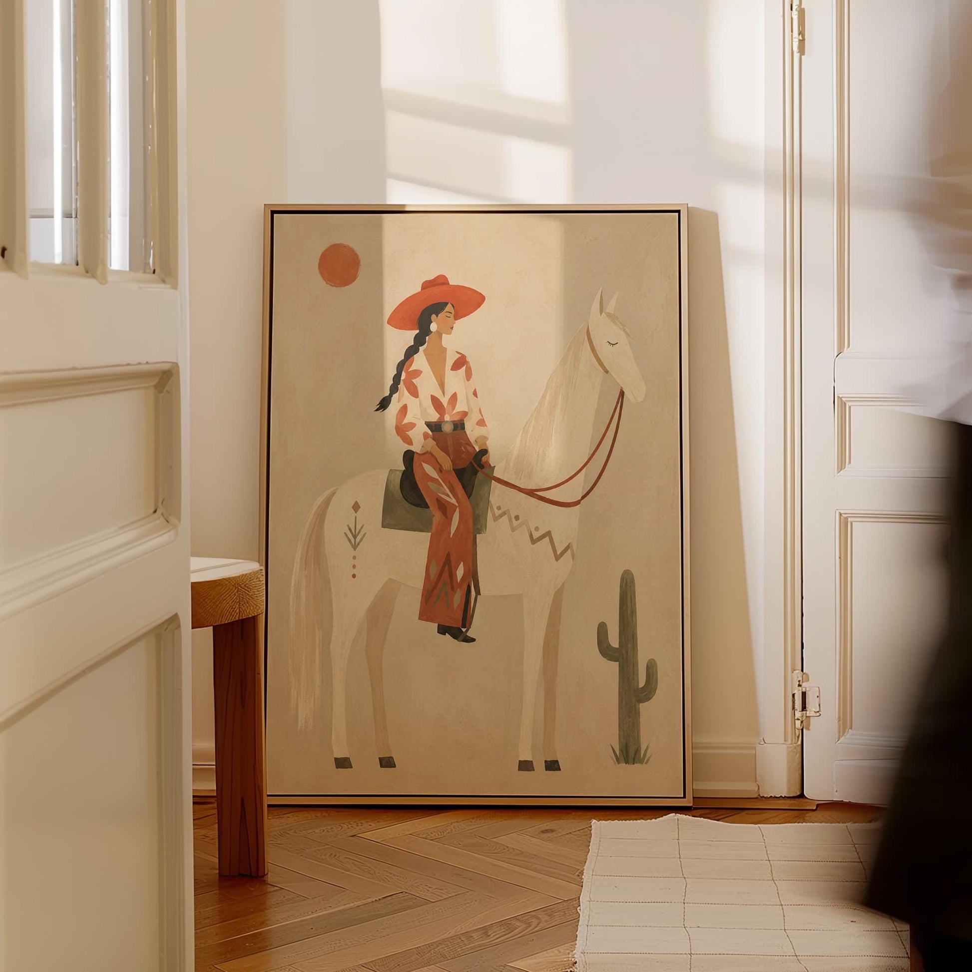 Cowgirl in a red hat sitting on a white horse beside a cactus in warm sand, canvas print shown to scale in a furnished room
